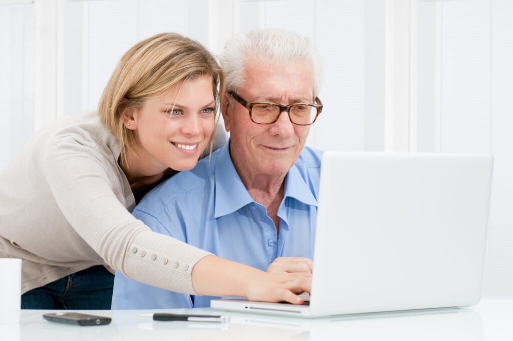 Young Woman Teaching Old Man New Computer Technology